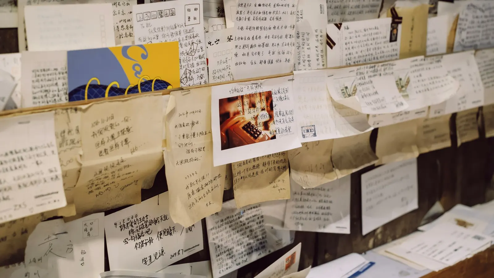A wall covered edge to edge with handwritten notes and letters pinned up by many different hands
