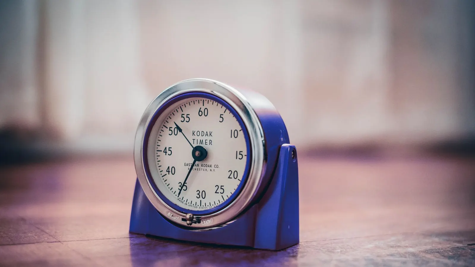 An old mechanical Kodak darkroom timer standing on a wooden surface, its dial numbered to sixty